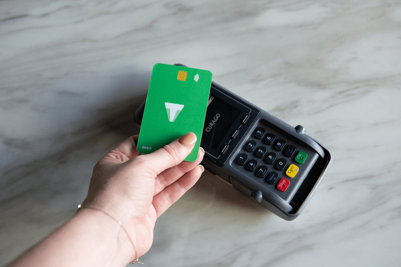 Hand holding a green credit card next to a calculator