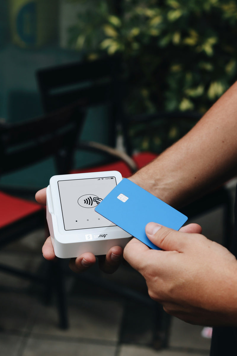 Blue debit card held over a portable card reader